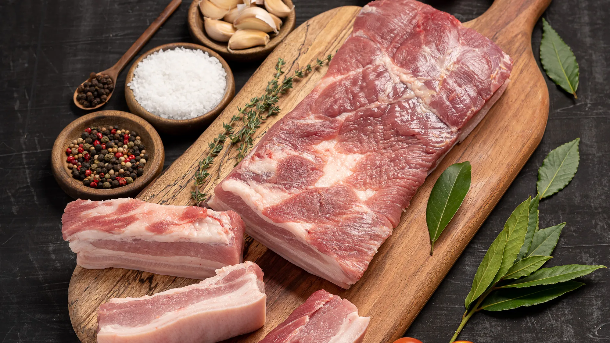 Tocino de cerdo entero y en tiras sobre tabla de madera